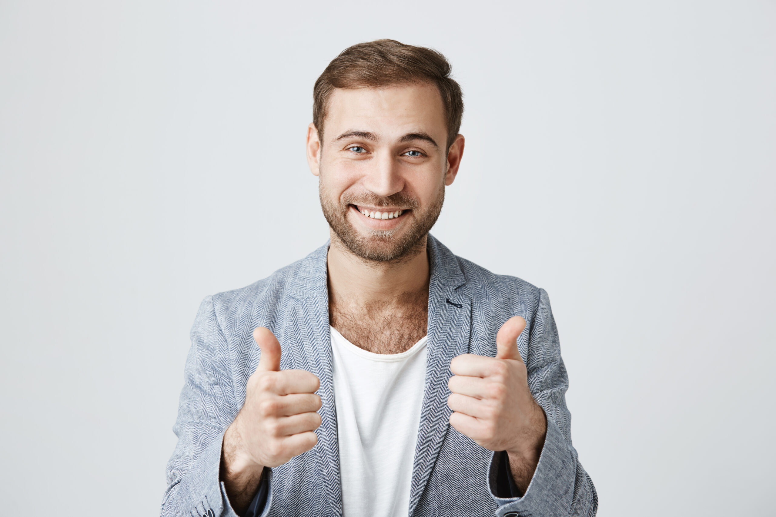 Portrait of stylish bearded man or customer with broad smile, looking at the camera with happy expression, showing thumbs-up with both hands, achieving professional goals. Body language Daniel